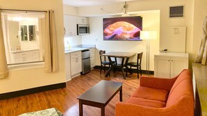 A compact living space with a kitchenette, a dining area, and a seating area with a sofa and a table.