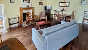 A spacious living room with a high wooden ceiling, a fireplace, a television, and a dining area with wooden furniture. - Country house with indoor pool, near Rochefort en terre; 2 stars. (Saint-Gravé)