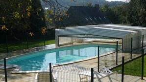 A swimming pool with a covered area, surrounded by a fence, and outdoor seating. - Country house with indoor pool, near Rochefort en terre; 2 stars. (Saint-Gravé)