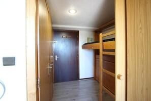 Cozy hallway leading to a room with a bunk bed and a door.