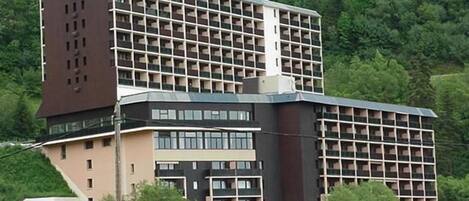 Un hotel de varios pisos con un diseño arquitectónico singular, que combina secciones rectangulares y curvas.