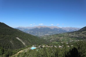 A mountainous landscape with a valley, houses, and a swimming pool. - Ski-in/ski-out & foot of the slopes, 1st floor, balcony, tv, ski locker, 39m², Les Orres (Les Orres)