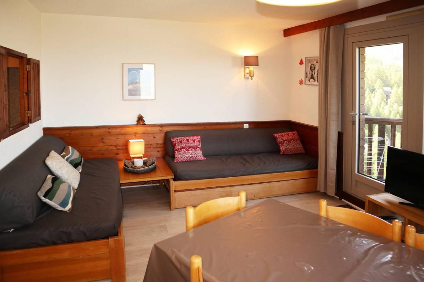 Un salon confortable avec un canapé, une petite table sur laquelle se trouve une lampe, et un téléviseur posé sur un meuble.