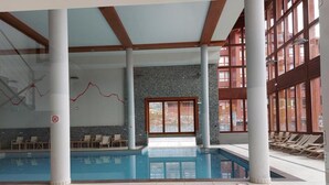 An indoor swimming pool with a hot tub, lounge chairs, and stone walls. - Ski-in/ski-out & foot of the slopes, 2nd floor, view open, fitness, swimming pool, balcony (Les Arcs)