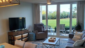 Een moderne woonkamer met een televisie, bank en eethoek.