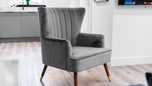 Un fauteuil moderne, doté d’un haut dossier et de pieds en bois, dans un salon contemporain.