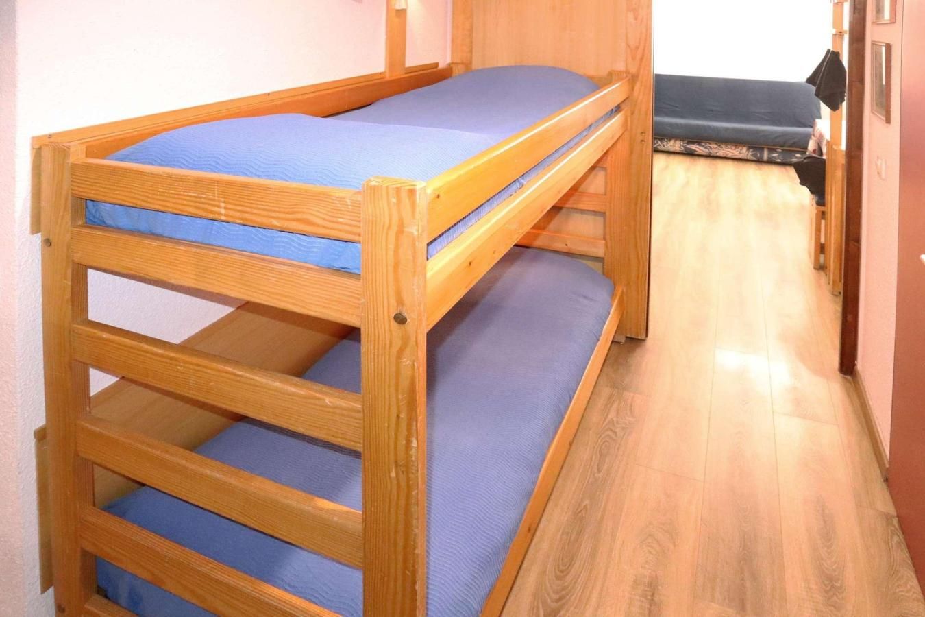 A bunk bed with a blue mattress and wooden frame.