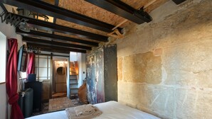 A bedroom with a bed, a radiator, a wooden wardrobe, and a staircase leading to an upper level. - Beautiful atypical hyper center loft (Nancy)