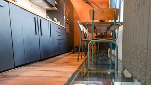 A modern kitchen with a glass dining table, wooden cabinets, and a patterned backsplash. - Beautiful atypical hyper center loft (Nancy)