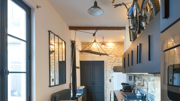 A modern kitchen with a long wooden countertop, a built-in oven, and a stone backsplash. - Beautiful atypical hyper center loft (Nancy)