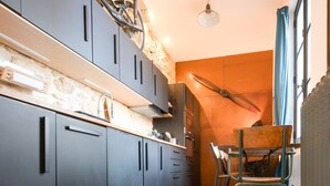 A modern kitchen with dark cabinets, a wooden countertop, and a dining area with a glass table and chairs. - Beautiful atypical hyper center loft (Nancy)
