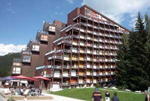 A multi-story hotel with balconies, outdoor seating, and a mountainous backdrop. - Ski-in/ski-out & foot of the slopes, 10th floor, balcony, tv, 25m², Les Arcs (Les Arcs)