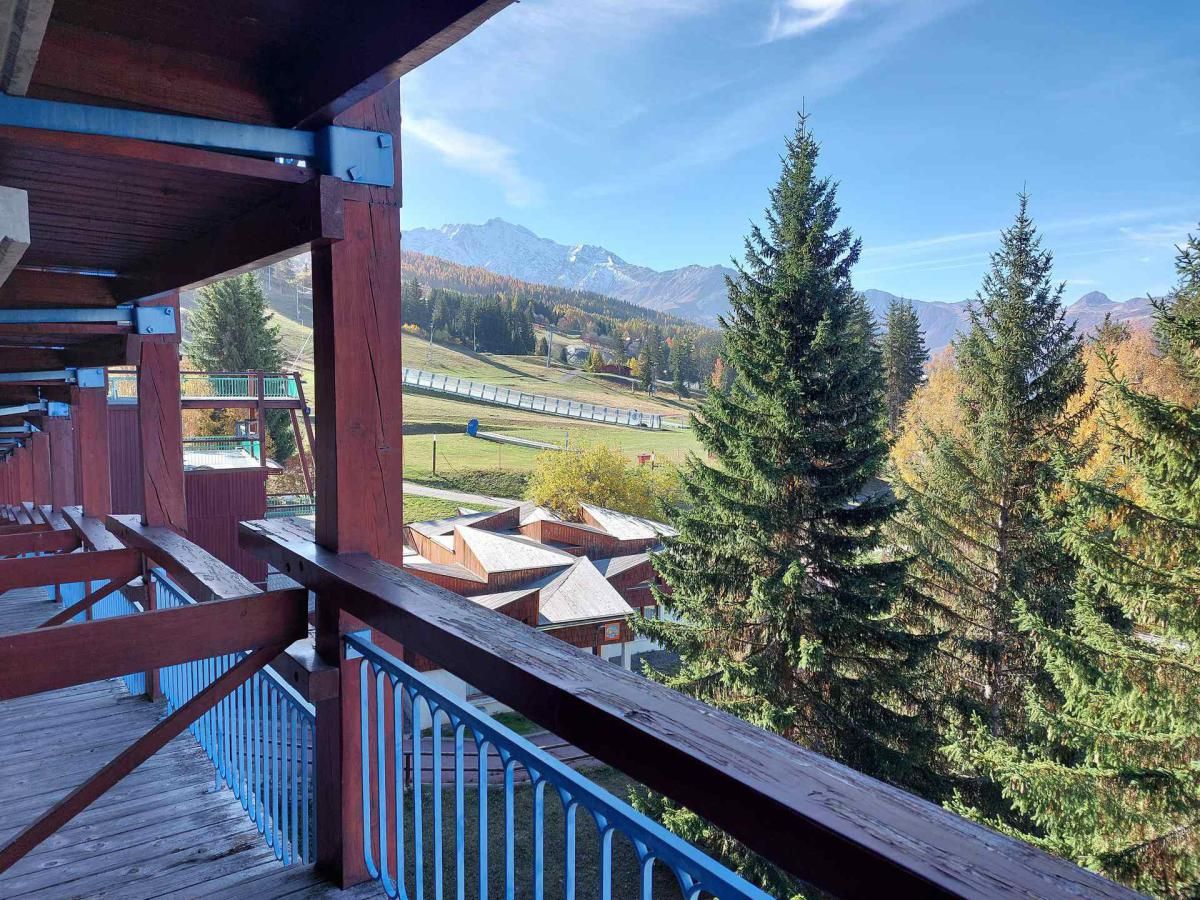 A wooden deck with a view of a mountain range and a train track.