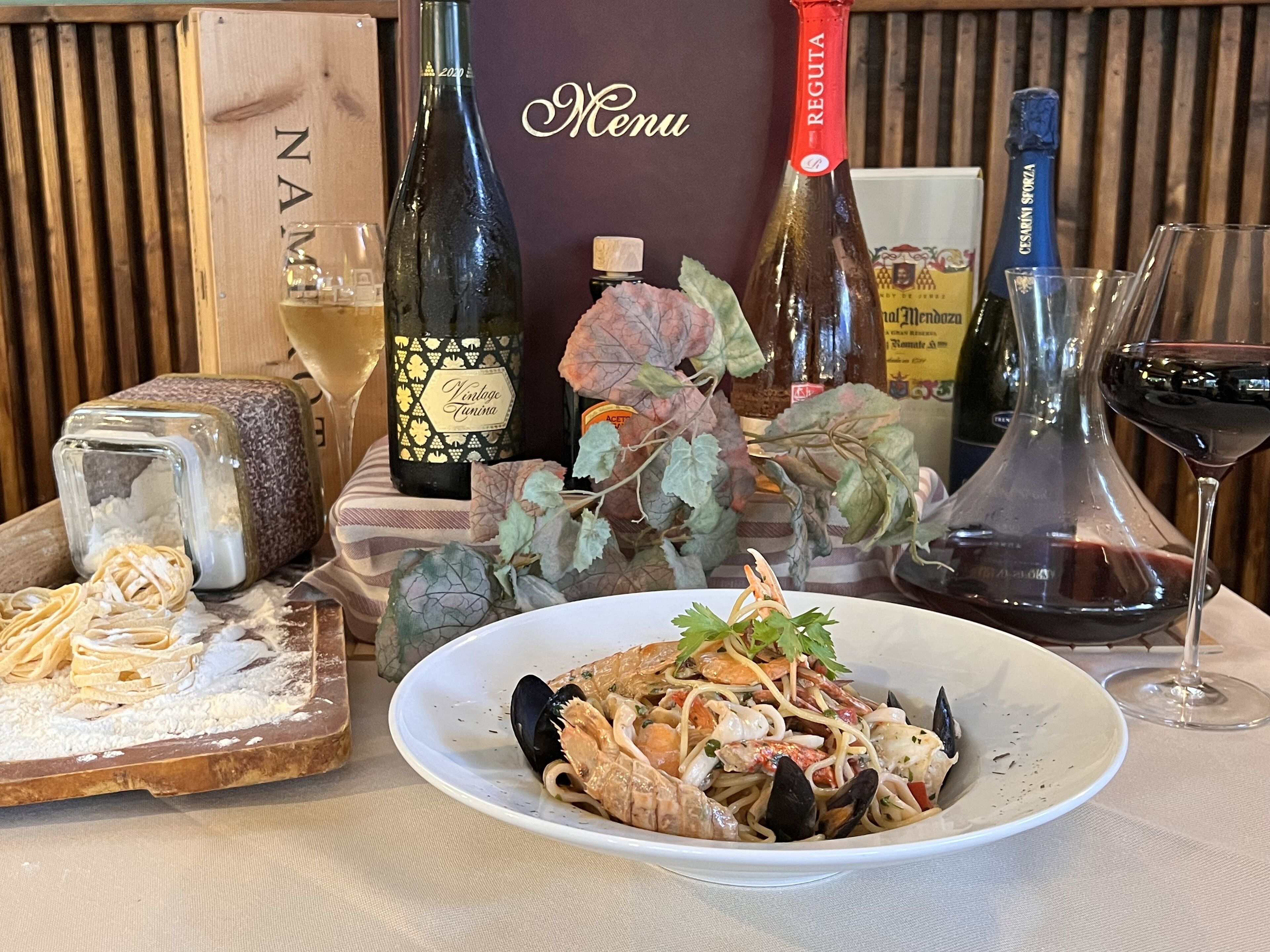 A seafood dish on a plate, a bottle of wine, and a menu board.