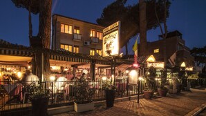 Un restaurante con terraza, un cartel que indica que está abierto y una bandera.