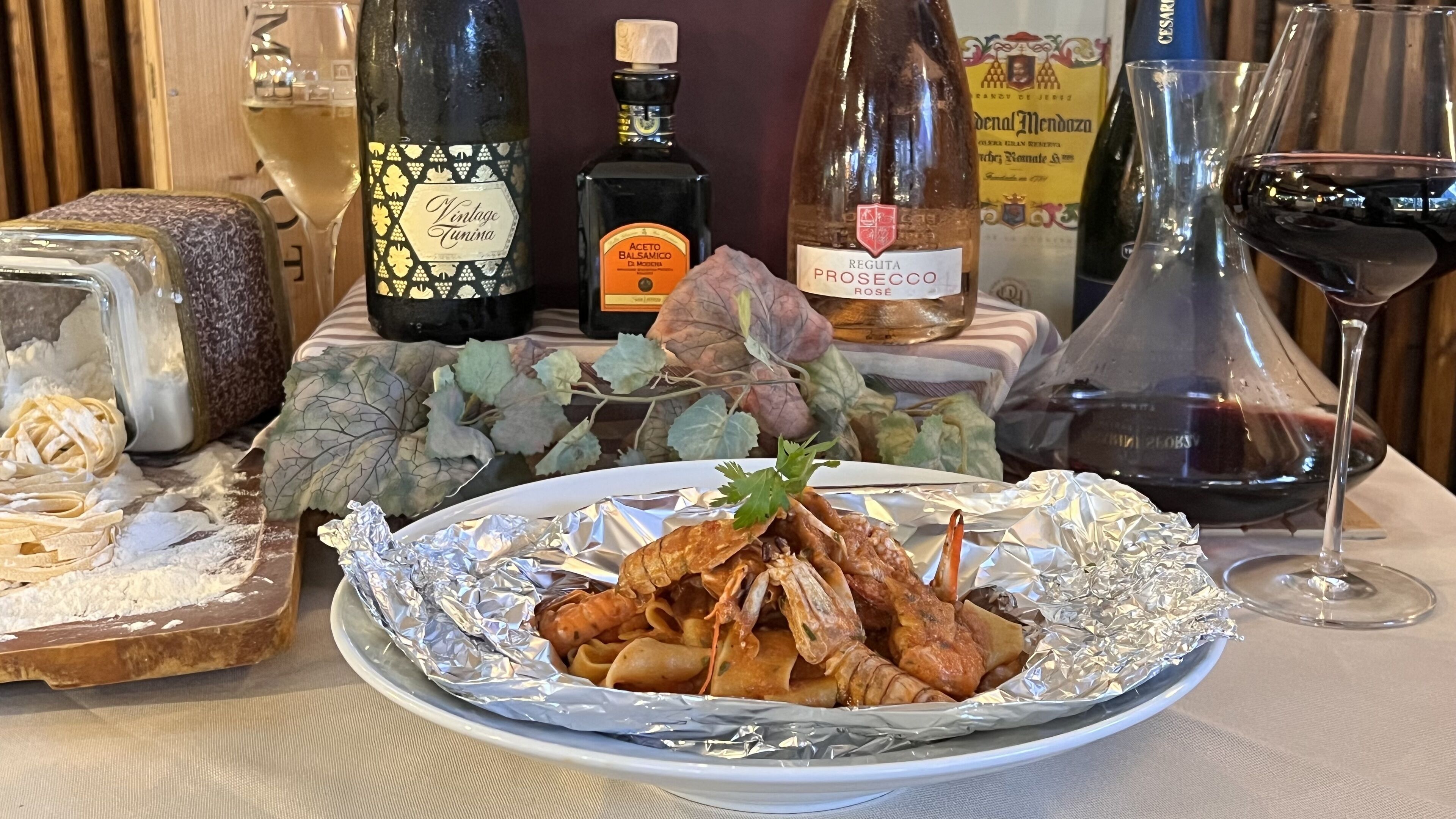 A dining table with a plate of seafood, wine bottles, and glasses.