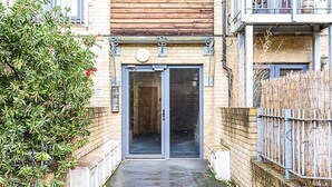 Une ruelle étroite menant à un bâtiment à la façade en bois et doté d’un portail en métal.