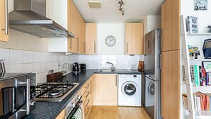 Une cuisine compacte équipée d’un four à micro-ondes, d’une cuisinière, d’un évier et d’un lave-linge.
