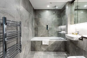 Een bad,  milieuvriendelijk toiletgerief, een haardroger, handdoeken