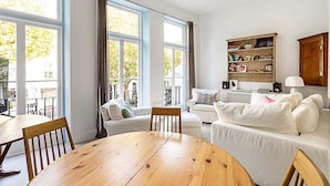 Ein geräumiger Wohnbereich mit einem Holzespeisetisch, zwei weißen Sofas und einem Bücherregal.