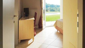 A room with a bed, a desk, and a chair. There is a door leading to a balcony with a view of a green landscape. - Magnificent home vacation wifi solution, sea, beach, last minute (Marche)