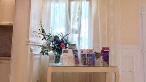 A reception area with a glass table displaying informational brochures, a vase with flowers, and a view through sheer curtains. - Magnificent home vacation wifi solution, sea, beach, last minute (Marche)