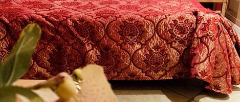 Une chambre d’hôtel avec un grand lit, des murs rouges et une petite table de chevet avec une lampe.
