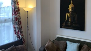 Een kamer met een bed, een bank, een Boeddha-schilderij, een lamp en een raam met gordijnen.