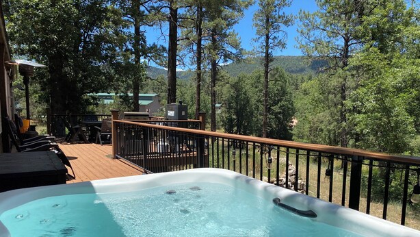 Un bain à remous sur une terrasse en bois, avec vue sur un paysage montagneux.