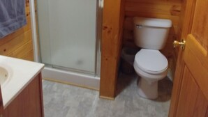 Une petite salle de bain compacte, équipée d’une douche, de toilettes et d’un lavabo.