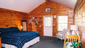 Une chambre confortable dans un chalet en rondins, avec un lit, une chaise, une table et une porte.