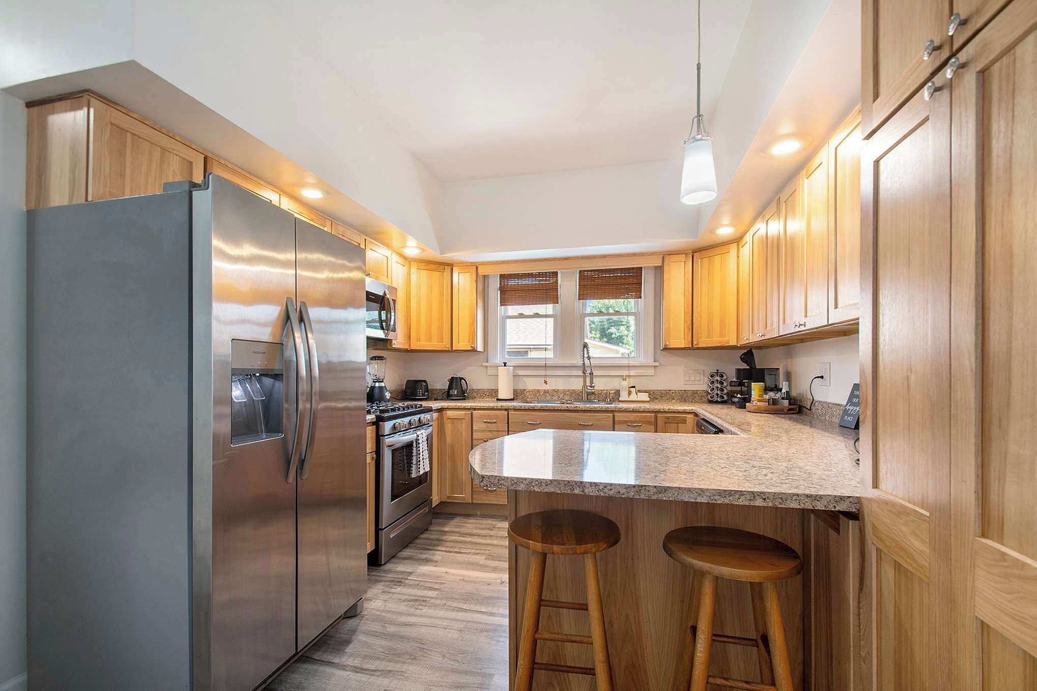 A modern kitchen with wooden cabinets, stainless steel appliances, and a granite countertop.
