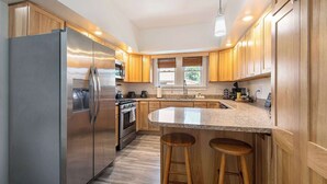 Una cocina moderna con armarios de madera, electrodomésticos de acero inoxidable y una encimera de granito.