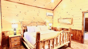 Ein Schlafzimmer aus Holz mit Bett, Nachttischen, Deckenventilator und Klimaanlage.