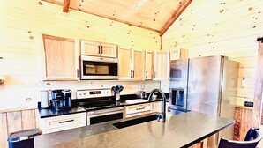 Een moderne keuken met houten kastjes, roestvrijstalen apparatuur en een centraal eiland met barstoelen.