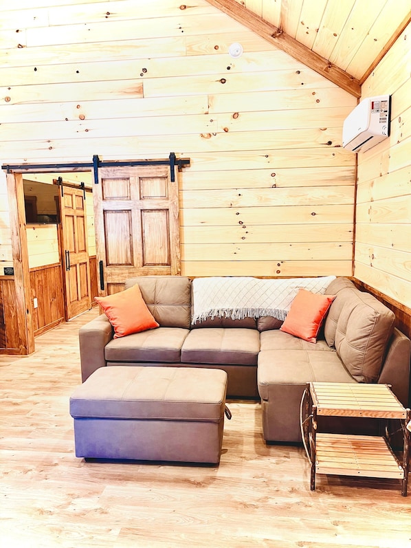 A cozy room with a sectional sofa, ottoman, and a small wooden table.