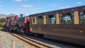 A vintage train with "Pullman" and "Bodygallen" written on the side, traveling on tracks with mountains in the background. - Ground Floor Apartment (Porthmadog)