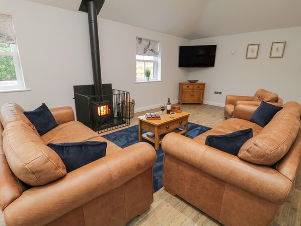 A living room with leather sofas, a fireplace, a television, and a wooden cabinet.