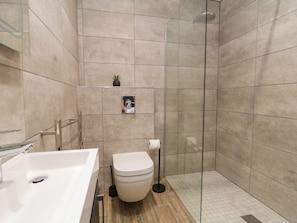 A modern bathroom with a glass shower enclosure, a white toilet, and a sink with a mirror. - Peacocks Rest (York)
