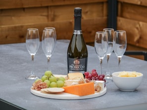 A table with a bottle of Prosecco, glasses, cheese, grapes, crackers, and a bowl of cheese. - Peacocks Rest (York)