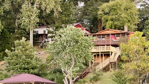 En fastighet vid sjön med en träbrygga, en överbyggd paviljong och ett hus med en balkong.