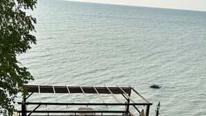 Una terraza de madera con mobiliario exterior, con vista a un cuerpo de agua.