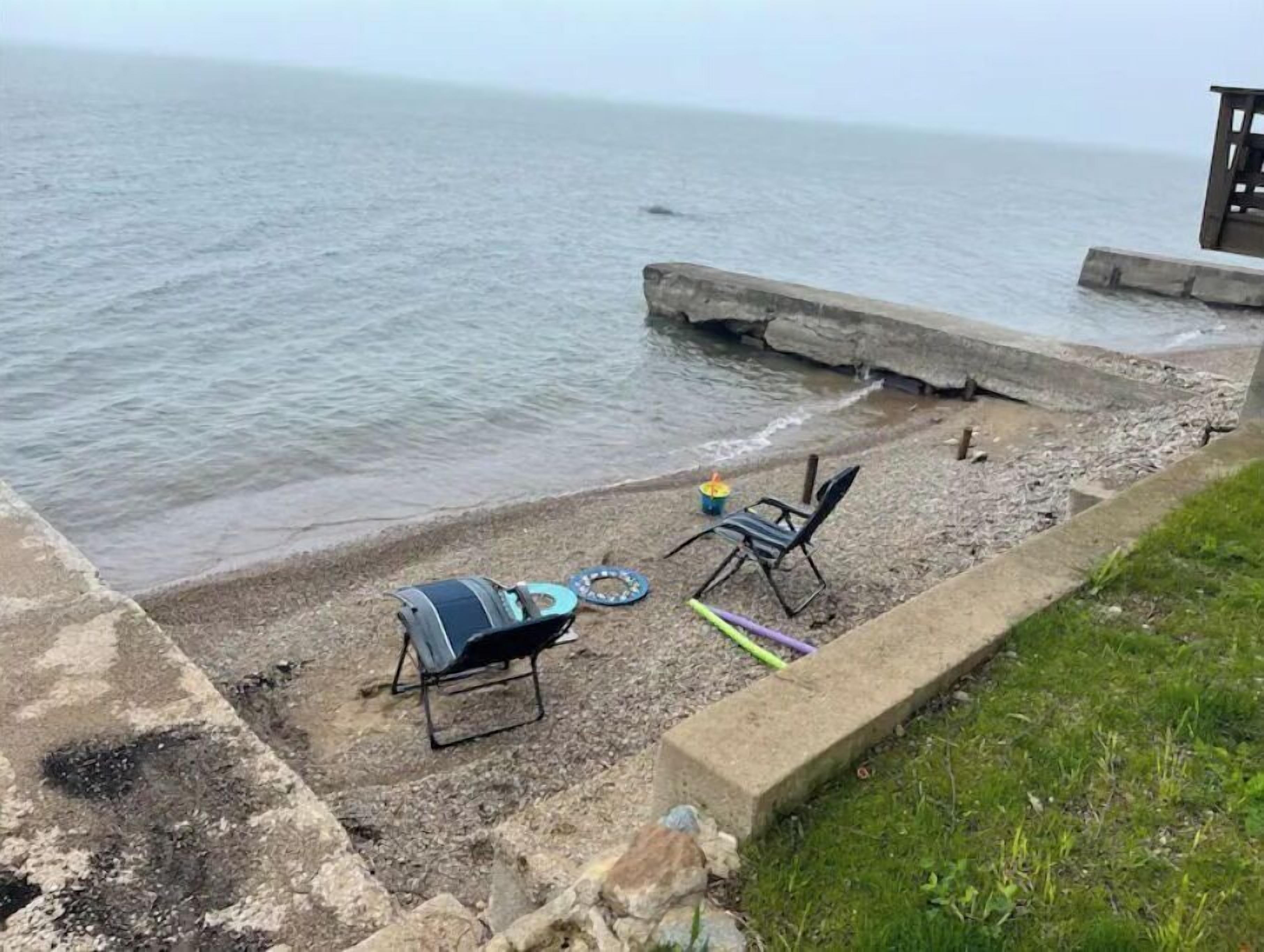 Une terrasse au bord de la plage, équipée d’un barbecue, de chaises et d’une petite table.
