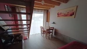 A room with a bed, a dining table with chairs, a kitchen area with appliances, and a painting on the wall. - Studio close to ocean and shops (Givrand)