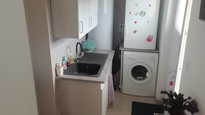 A compact kitchen with a sink, cabinets, a washing machine, and a refrigerator. - Studio close to ocean and shops (Givrand)