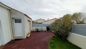 A compact outdoor area with a gravel surface, a small table with chairs, and a potted plant. - Studio close to ocean and shops (Givrand)