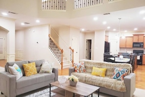 Relax in this inviting living area with two sofas, a coffee table, and a staircase leading to an upper level.