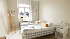 Ein Schlafzimmer mit zwei Betten, einem Fenster mit Blick, einem Nachttisch und einem kleinen Schreibtisch.