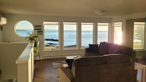En stue med havudsigt, et rundt vindue og en sofa.