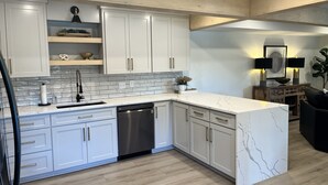 A modern kitchen with white cabinets, a marble countertop, and a dishwasher. - *New 3BR/2BA* ~ 200 ft Lake Frontage ~ Lakehaven (Hot Springs)